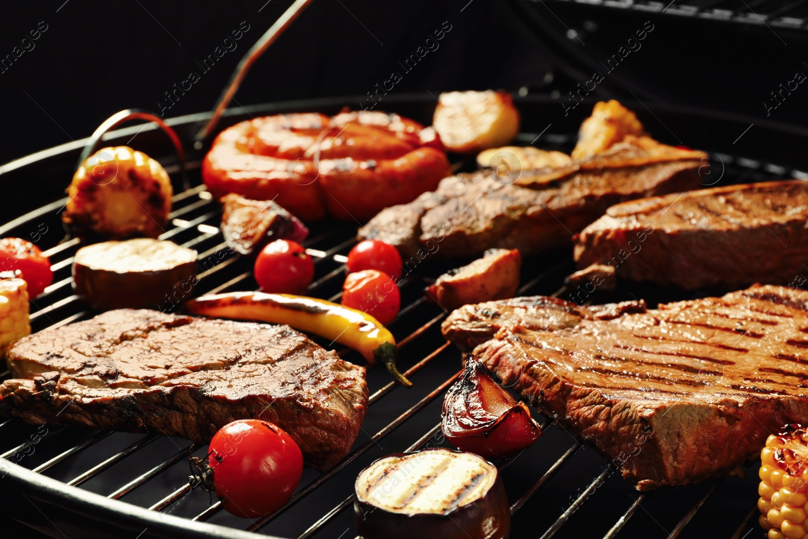 Photo of Fresh grilled meat steaks and vegetables on barbecue grate
