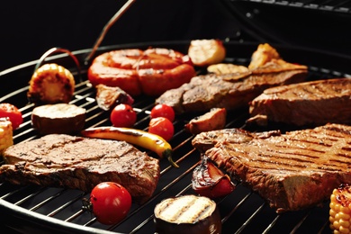 Fresh grilled meat steaks and vegetables on barbecue grate