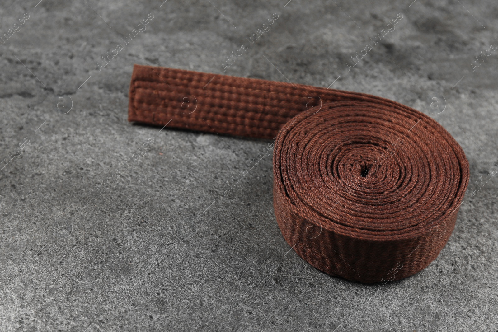 Photo of Brown karate belt on gray textured background, space for text