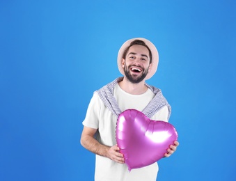 Photo of Portrait of young man with heart shaped balloon on color background