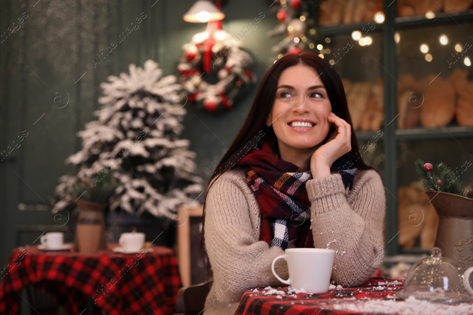 Photo of Beautiful woman at table in decorated cafe. Christmas celebration