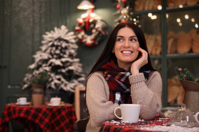 Photo of Beautiful woman at table in decorated cafe. Christmas celebration