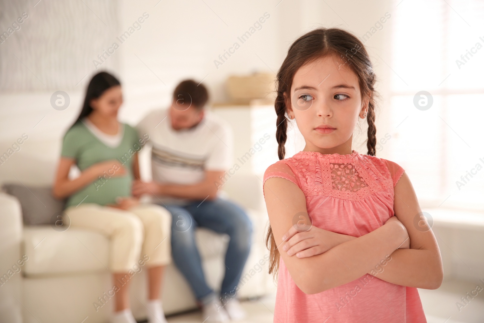 Photo of Unhappy little girl and her father with pregnant mother at home. Feeling jealous towards unborn sibling