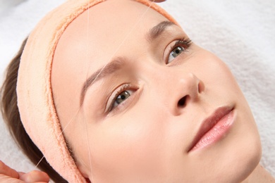 Young woman having eyebrow correction procedure in beauty salon, closeup