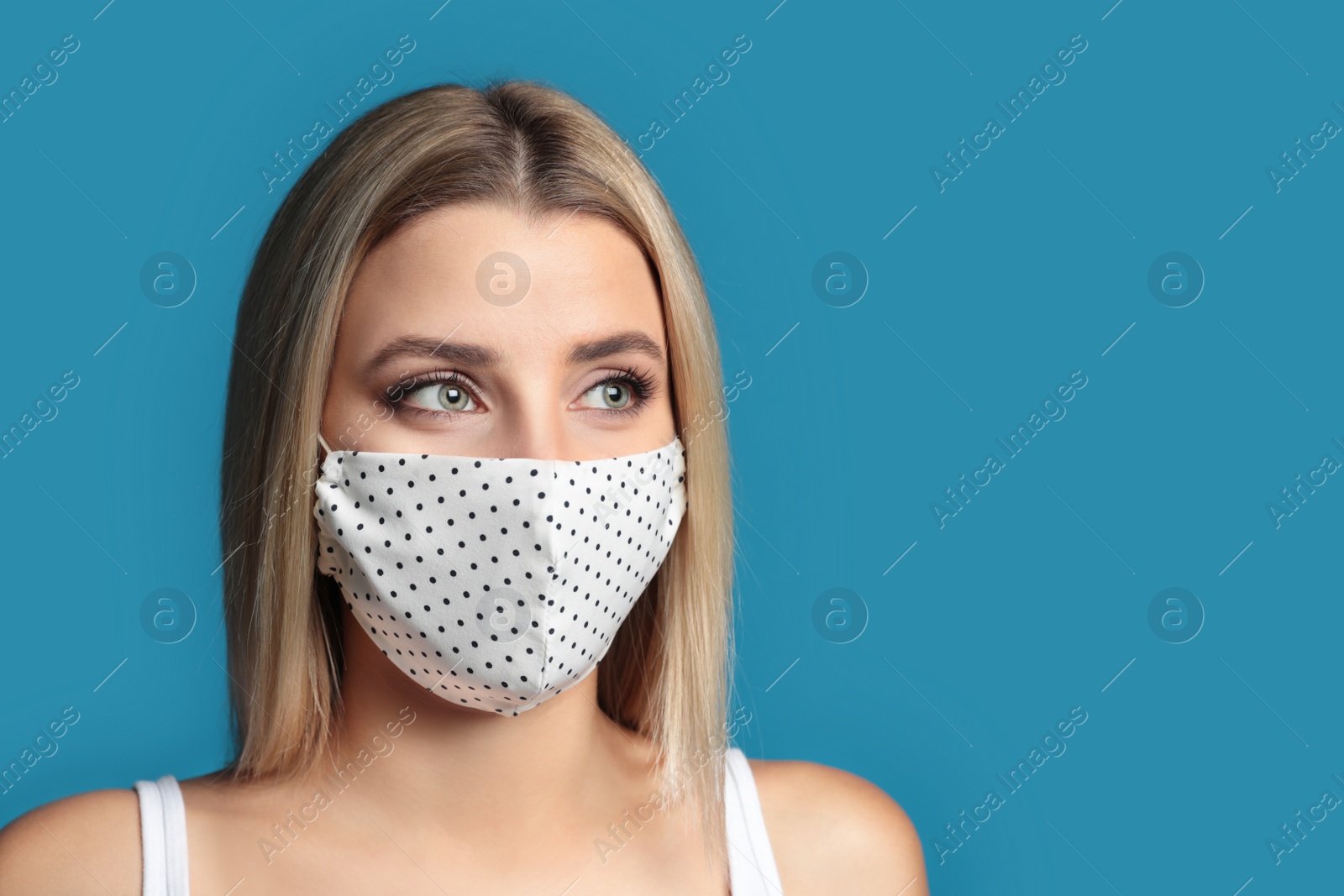 Photo of Young woman in protective face mask on blue background. Space for text