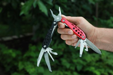 Photo of Man holding compact portable multitool outdoors, closeup