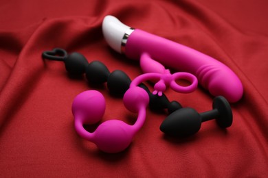 Photo of Pink and black sex toys on red fabric