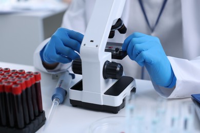 Photo of Scientist working with microscope in laboratory, closeup