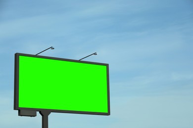 Image of Chroma key compositing. Big empty billboard with green screen against blue sky. Mockup for design