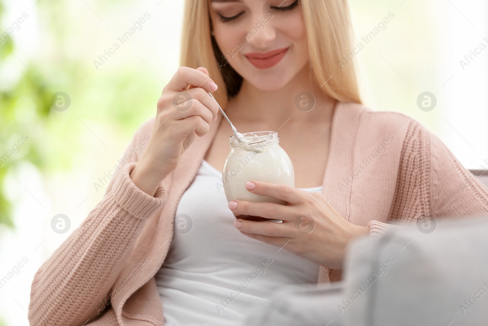 Photo of Young woman with yogurt indoors