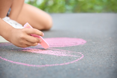 Photo of Little child drawing heart with chalk on asphalt, closeup