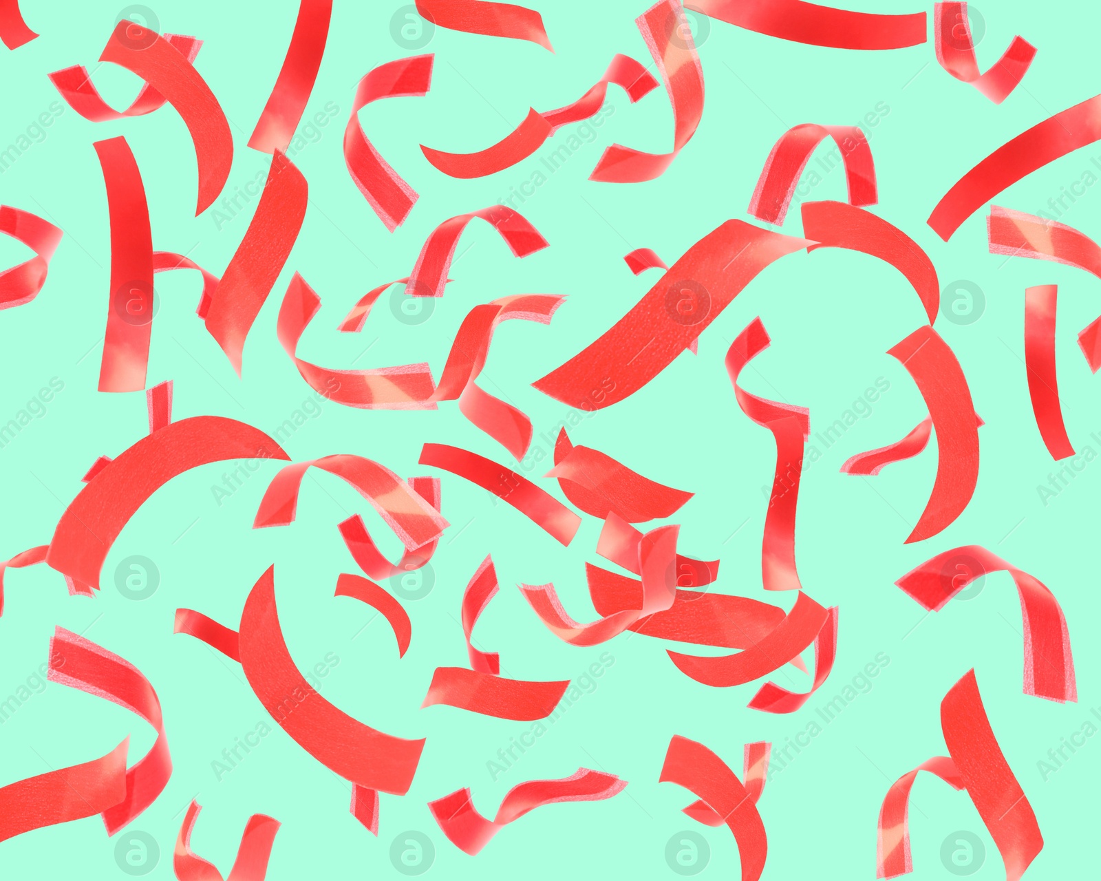 Image of Bright red confetti falling on turquoise background