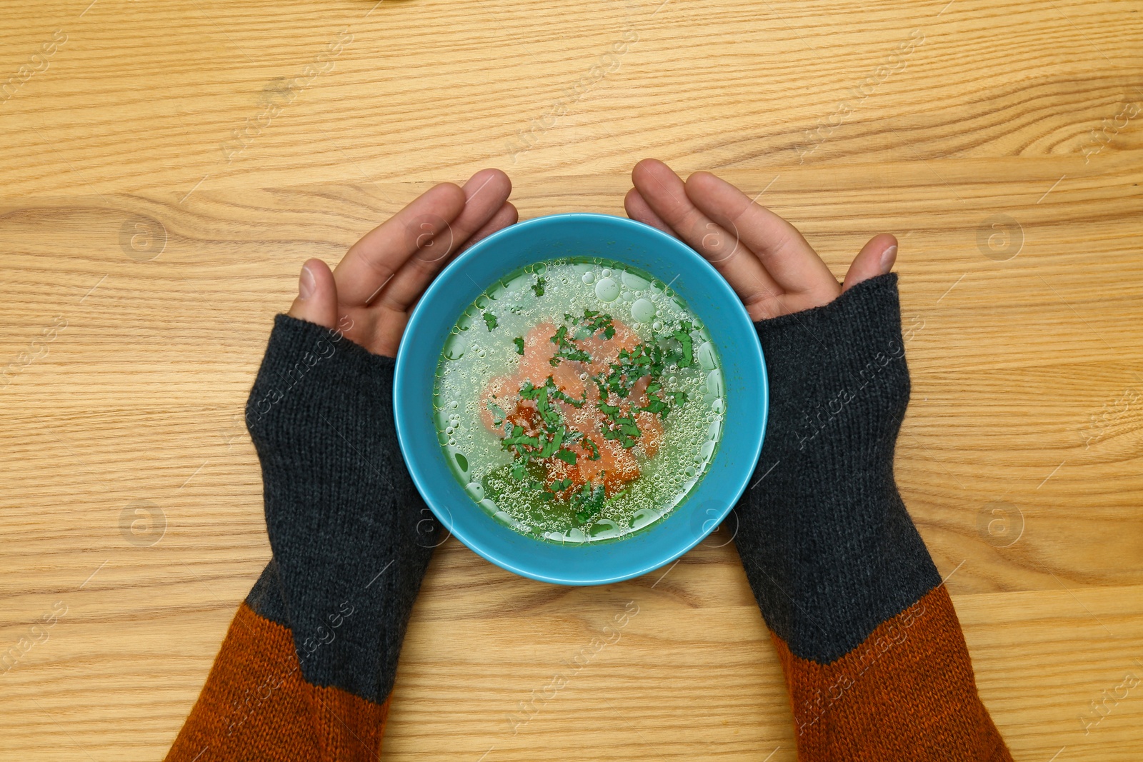 Photo of Man with bowl of soup at wooden table, top view. Flu treatment