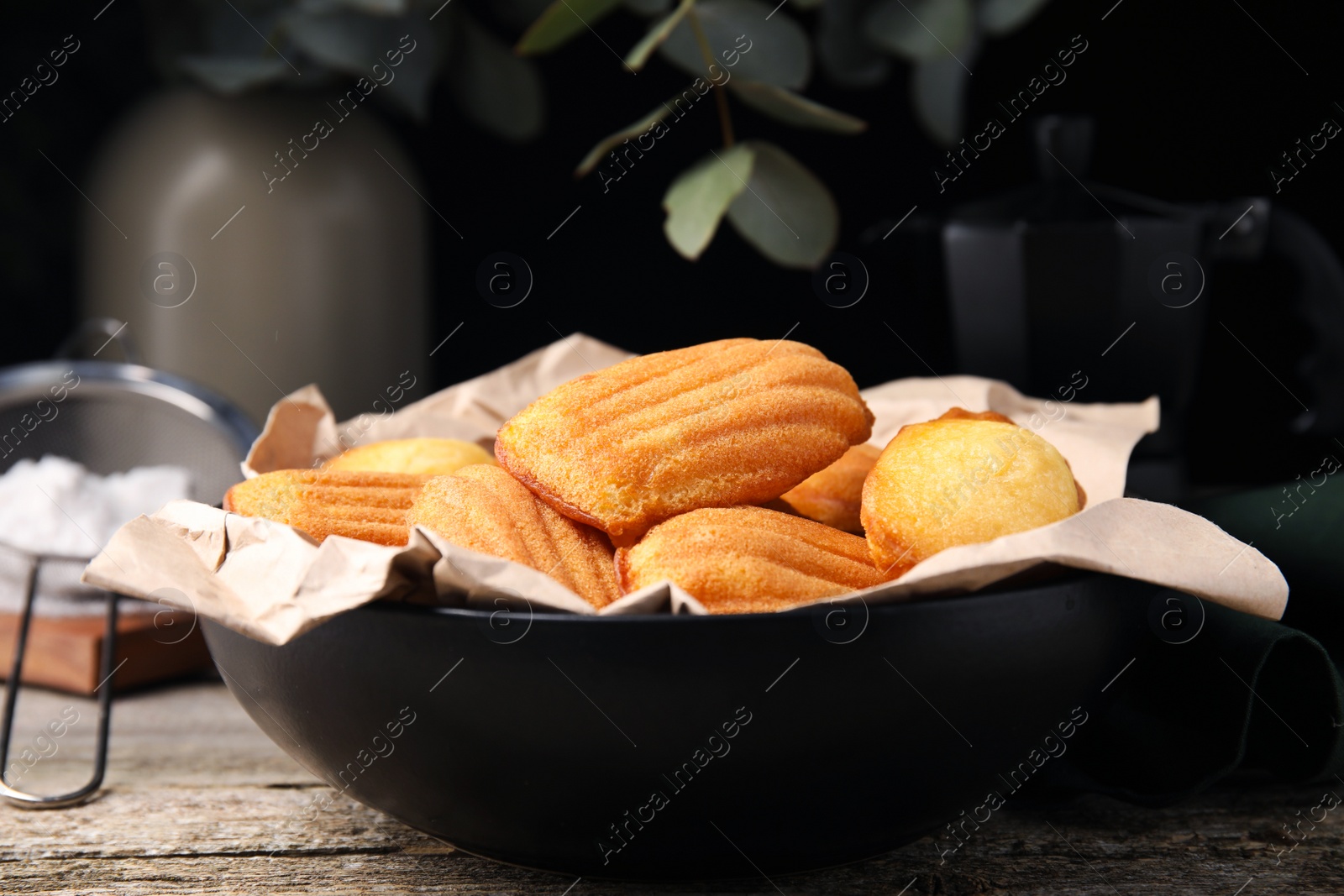 Photo of Delicious madeleine cakes in bowl on wooden table, closeup