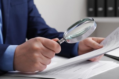 Photo of Man looking at document through magnifier at white table, closeup. Searching concept