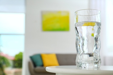 Glass of water on table in room, space for text. Refreshing drink