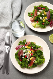 Tasty fresh kale salad on grey table, above view