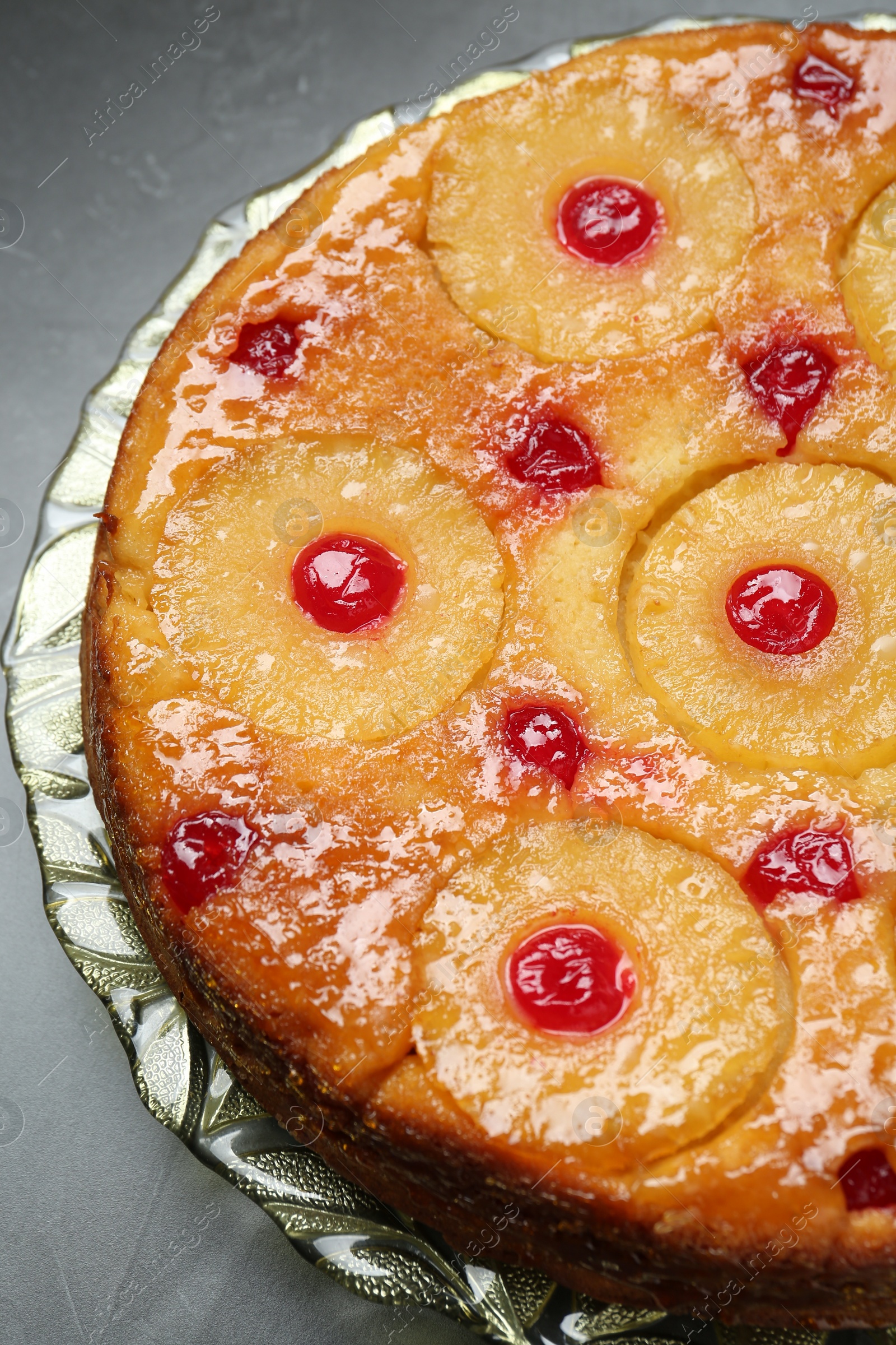 Photo of Plate with tasty pineapple cake on grey textured table, closeup