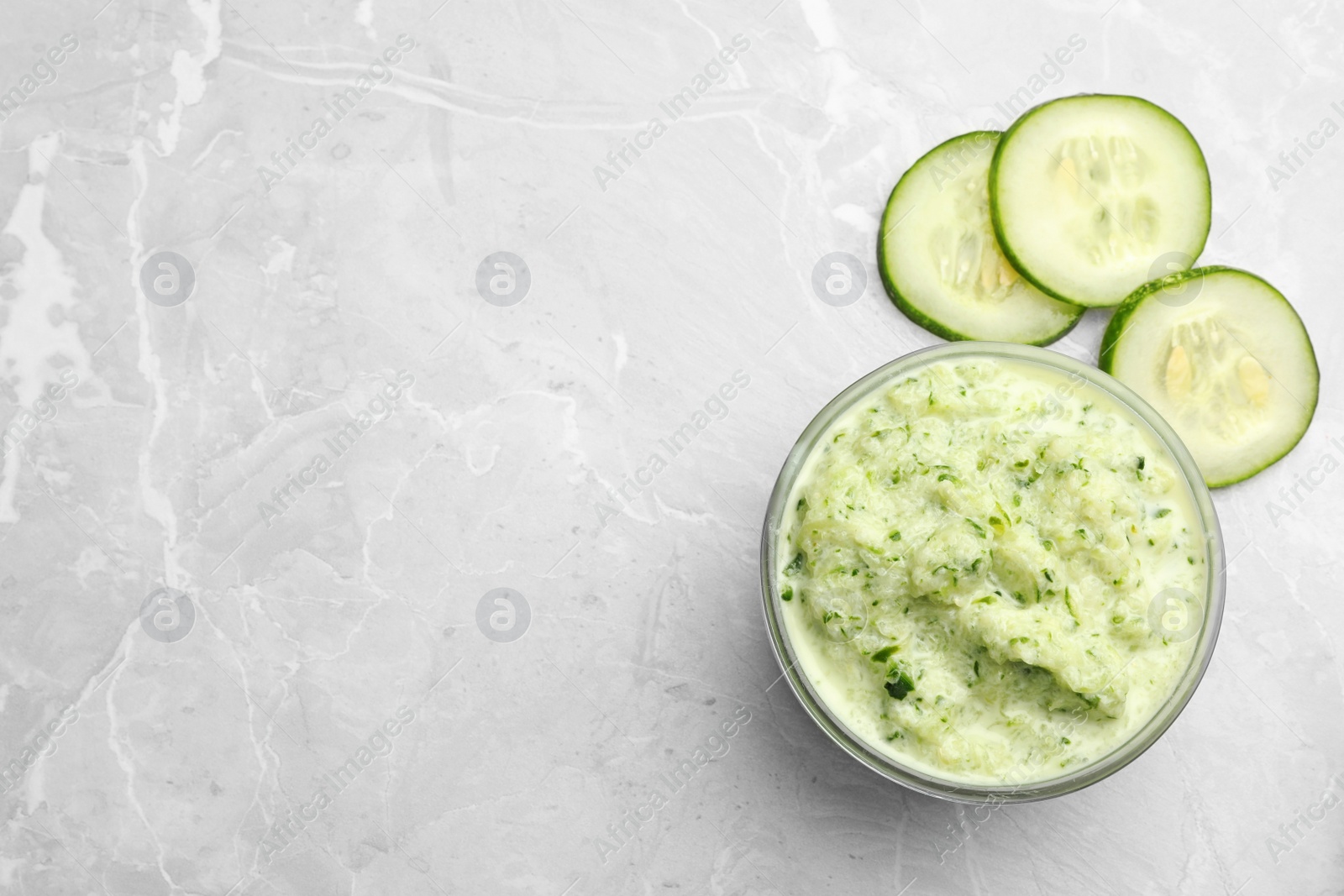 Photo of Handmade face mask and cucumber slices on light marble table, flat lay. Space for text