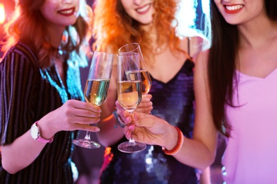 Young women chinking glasses in nightclub, closeup. Birthday party