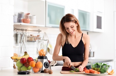 Young woman preparing tasty healthy smoothie at table in kitchen