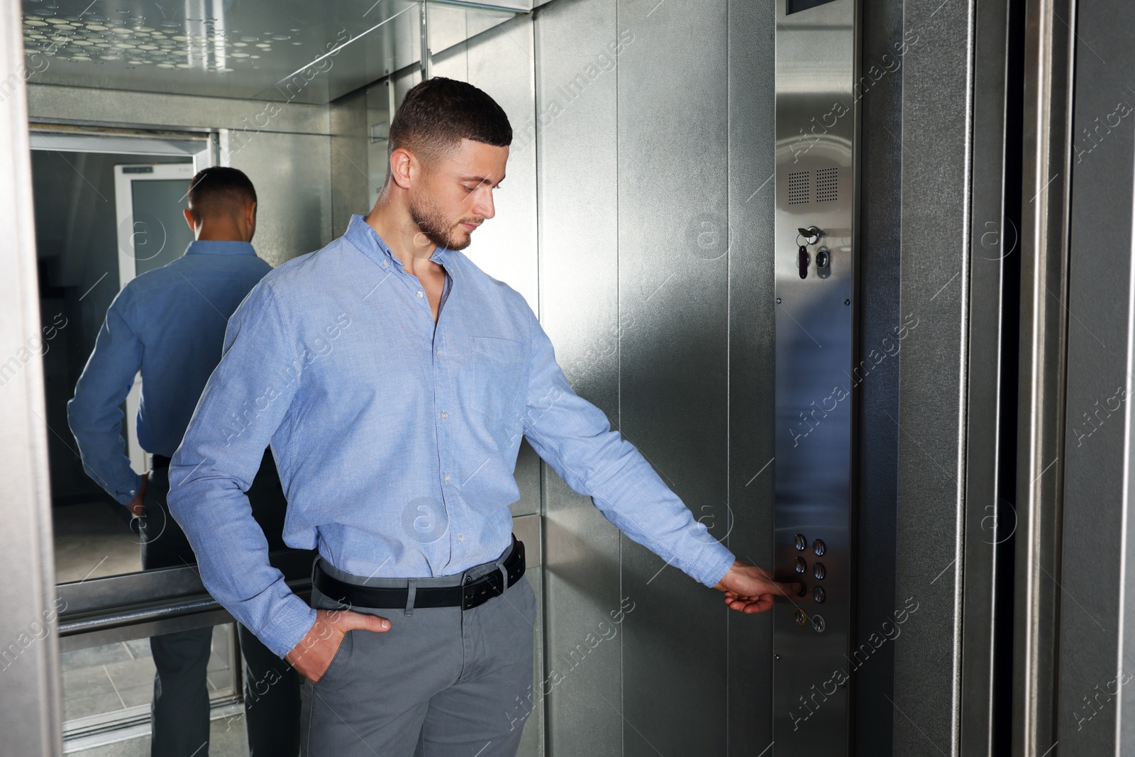 Photo of Attractive young businessman choosing floor in elevator