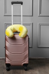 Photo of Yellow travel pillow on suitcase near light wall indoors