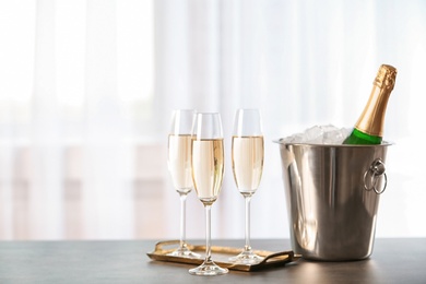 Photo of Glasses with champagne and bottle in bucket on table