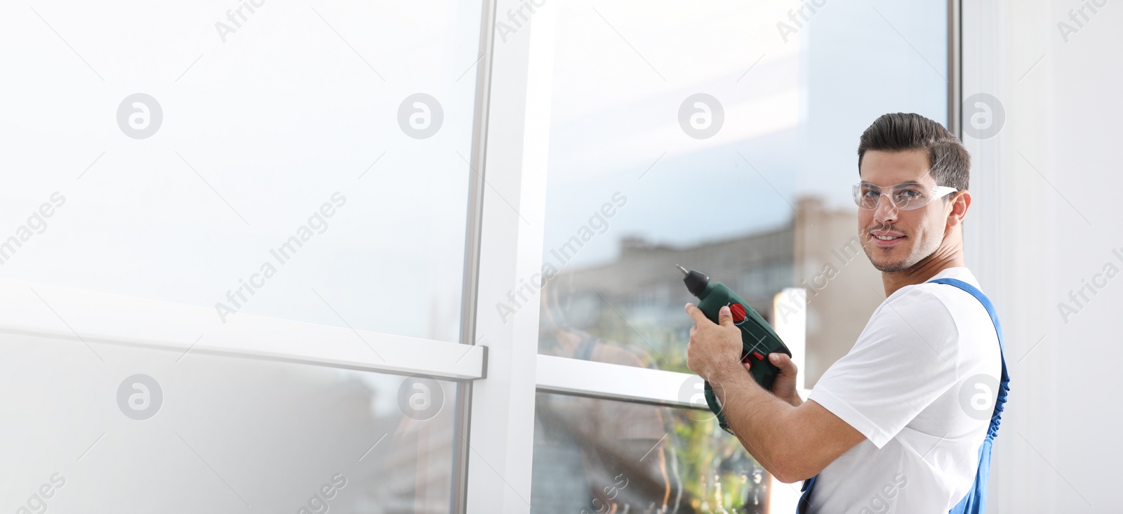 Image of Construction worker repairing plastic window with electric screwdriver indoors, space for text. Banner design