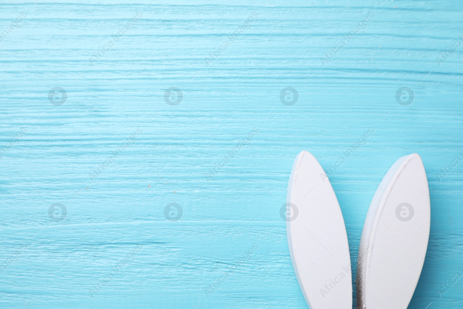 Photo of Decorative bunny ears and space for text on light blue wooden background, flat lay. Easter holiday