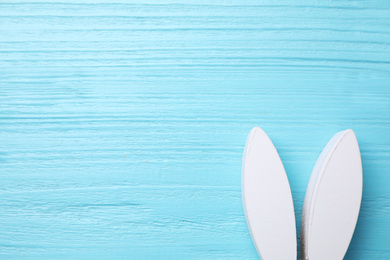 Photo of Decorative bunny ears and space for text on light blue wooden background, flat lay. Easter holiday