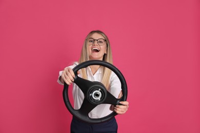 Photo of Emotional young woman with steering wheel on crimson background