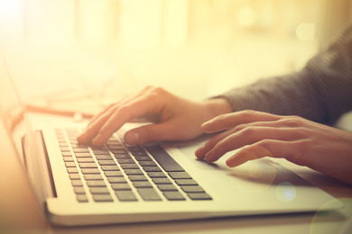 Woman working with laptop at table indoors, closeup