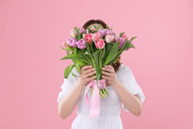 Photo of Young woman holding bouquet of beautiful tulips on pink background