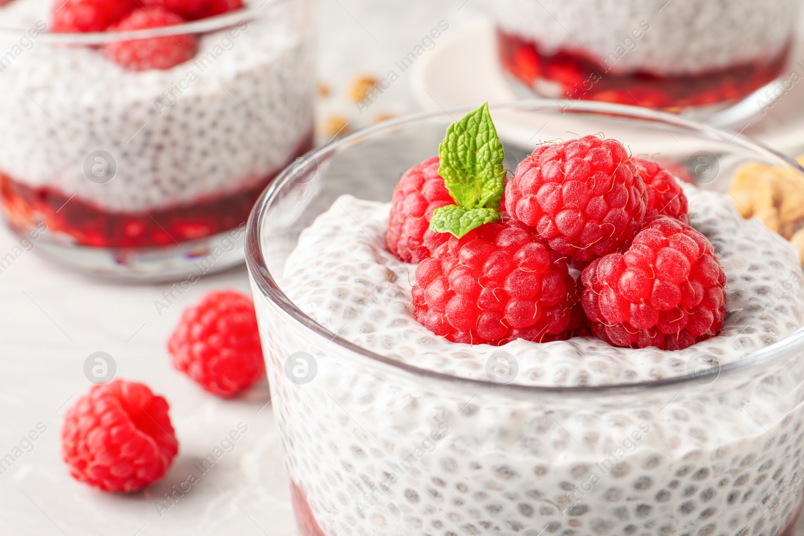 Photo of Delicious chia pudding with raspberries and mint in glass, closeup