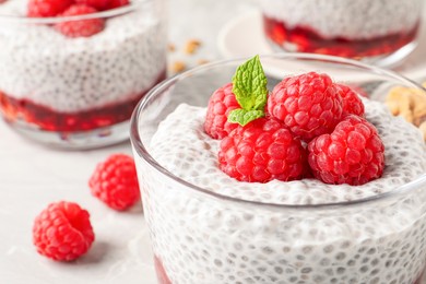 Photo of Delicious chia pudding with raspberries and mint in glass, closeup