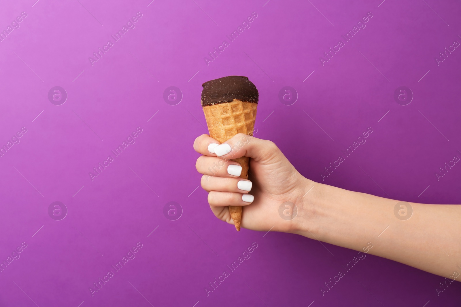 Photo of Woman holding yummy ice cream on color background. Focus on hand