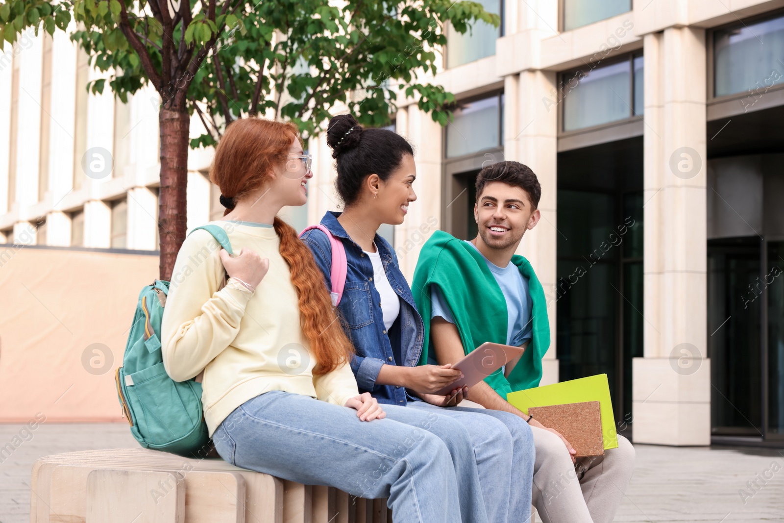 Photo of Happy young students with backpacks learning together outdoors