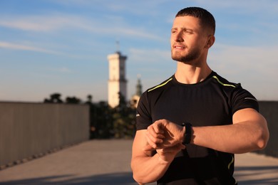 Attractive serious man checking pulse after training outdoors. Space for text