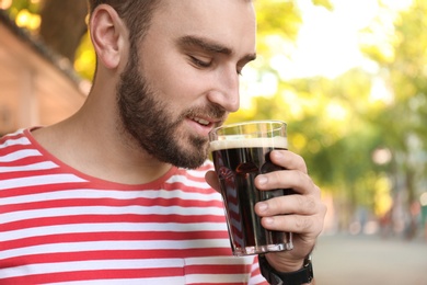 Handsome man with cold kvass outdoors, closeup. Traditional Russian summer drink