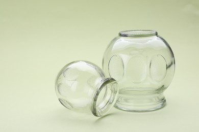 Photo of Glass cups on light olive background, closeup. Cupping therapy