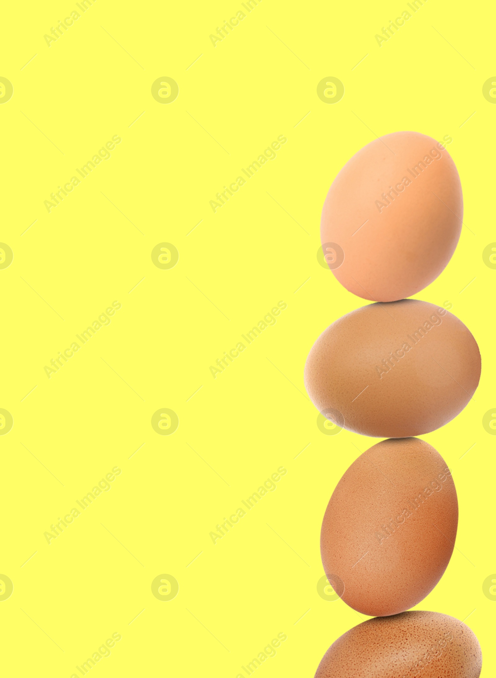 Image of Stacked fresh chicken eggs against light yellow background. Space for text