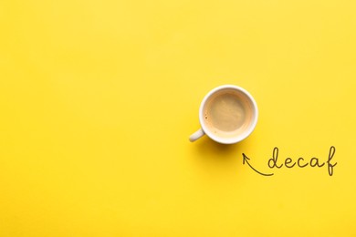 Photo of Word Decaf and cup of coffee on yellow background, top view. Space for text