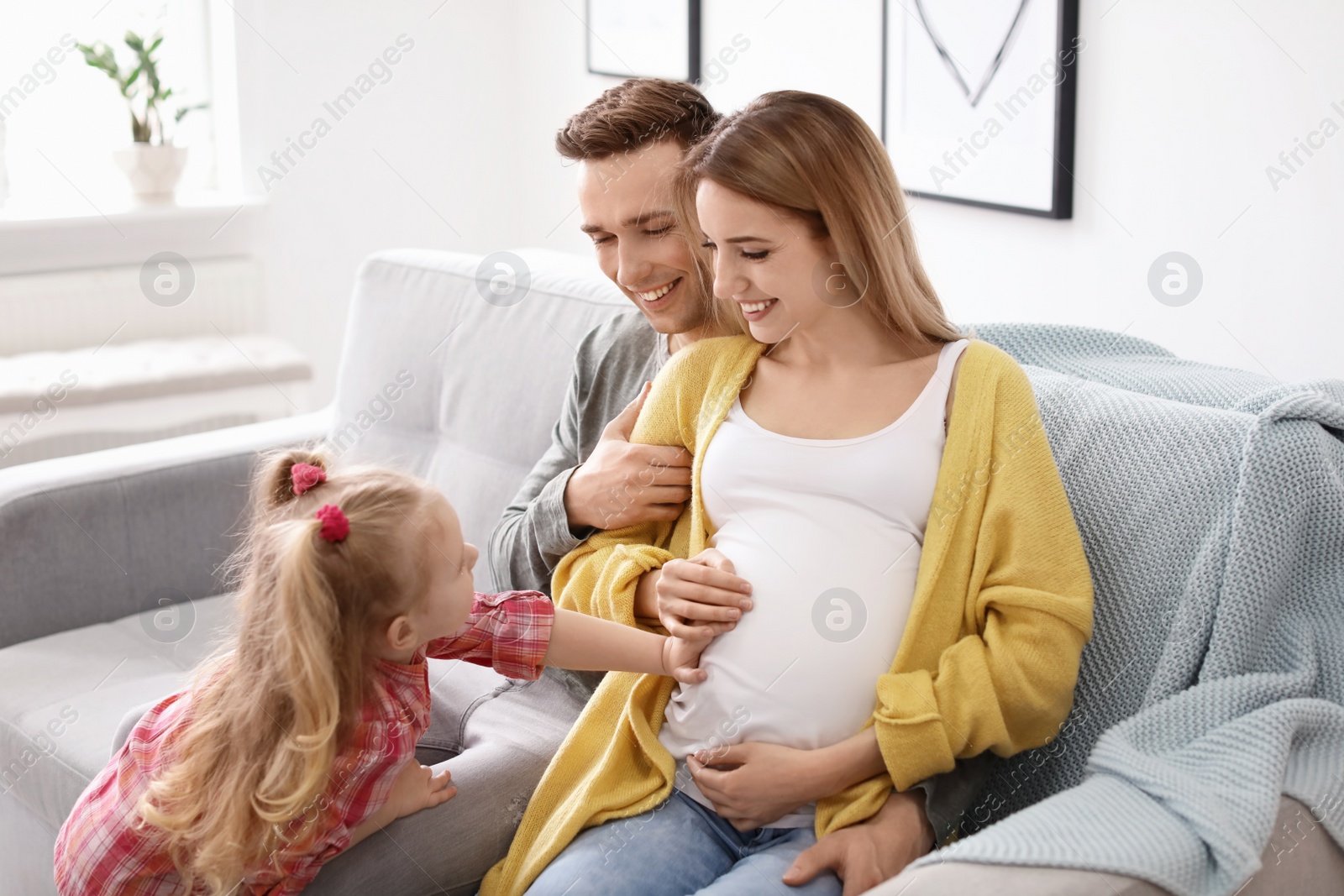 Photo of Young pregnant woman with her family at home