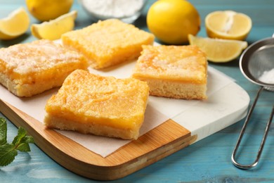 Photo of Tasty lemon bars and mint on light blue wooden table, closeup