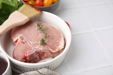 Photo of Raw meat, thyme and brush with marinade on white tiled table, closeup. Space for text