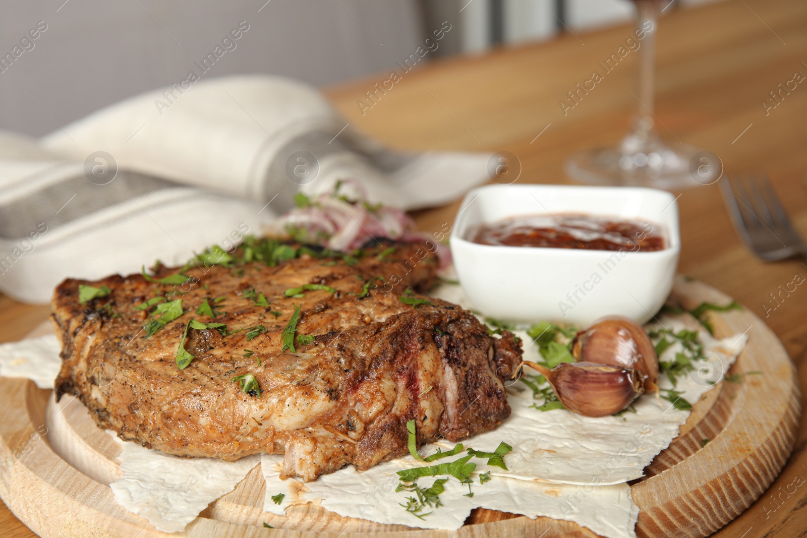 Photo of Delicious grilled pork chop on wooden board, closeup