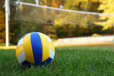 Photo of Colorful ball on grass near volleyball court outdoors