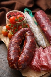 Different types of tasty sausages and tomatoes on table, closeup