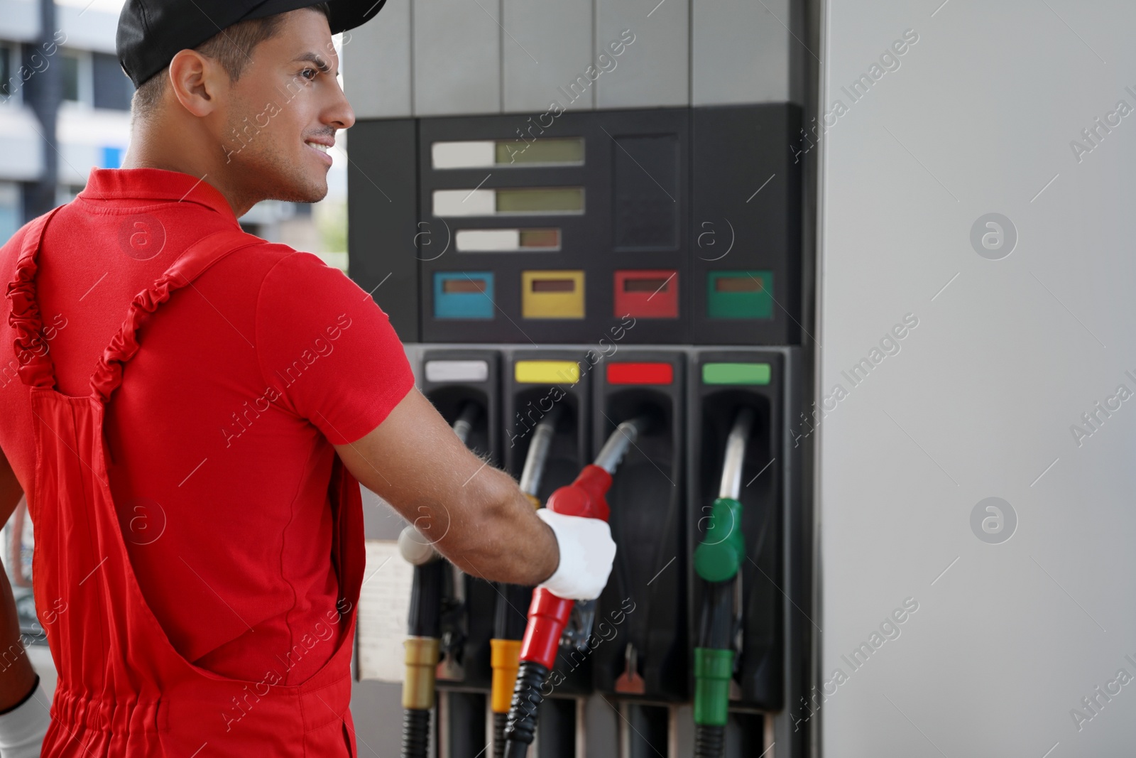 Photo of Worker taking fuel pump nozzle at modern gas station